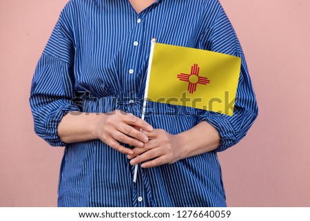 New Mexico state flag. Close up of hands holding New Mexico flag.