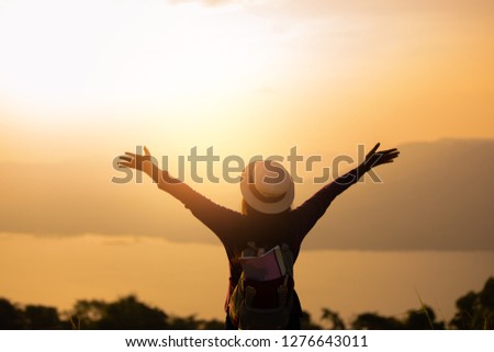 traveler woman standing with raised arms sunset on peak mountain.