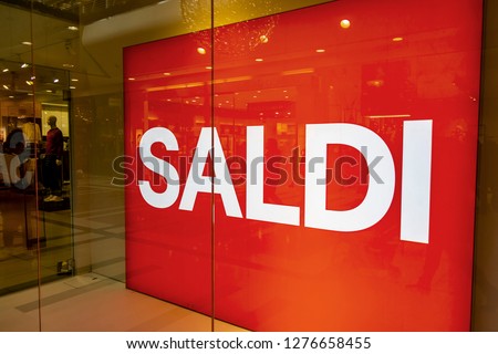 big red writing "saldi", sale, in the window of a clothing store and Italian fashion, during the winter sales of January.