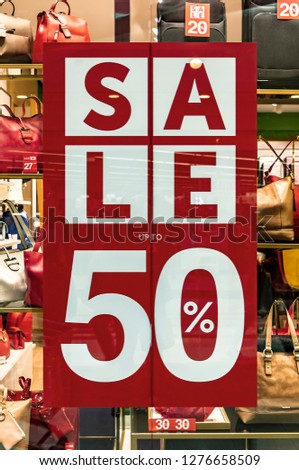 Red sign with the words "Sale up to 50%", in the window of an Italian bags and fashion store, during the winter sales in January. Bags with price tag and discount