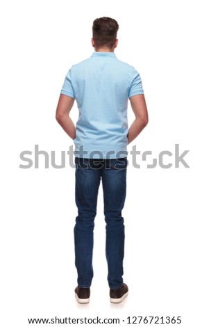 rear view of relaxed casual man wearing blue polo shirt while standing on white background, full length picture
