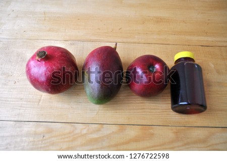 different fruits and a bottle of juice on a wooden surface - mango, pomegranate, apple, avocado, tangerine