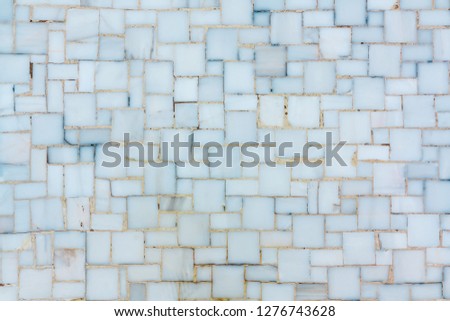 Wall lined with small bright ceramic or marble tiles, texture.