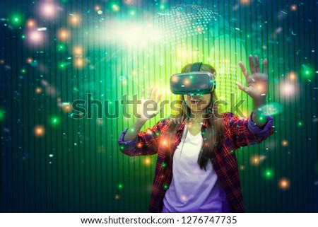 Portrait of young woman using virtual reality or VR for gaming and video that showing stars in the galaxy space. Future technology for entertainment at home.