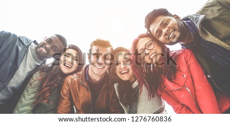 Happy friends from diverse cultures and races taking photo making funny faces - Youth, millennial generation and friendship concept with young people having fun together - Main focus on right guys