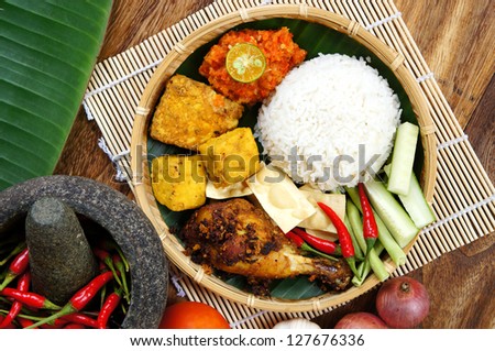 A plates of Delicious 'Ayam Penyet' with 'Sambal Belacan' and 'Tempe'- local flavor Royalty-Free Stock Photo #127676336