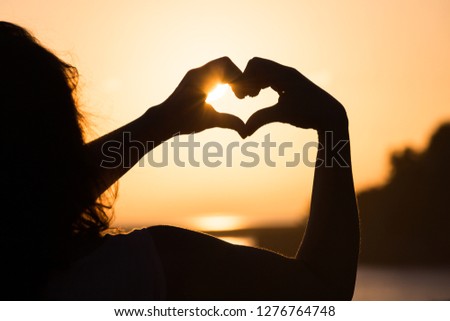 The heart of the fingers on sunset sky background
