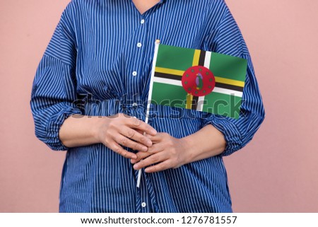 Dominican flag. Close up of hands holding national flag of Dominica.