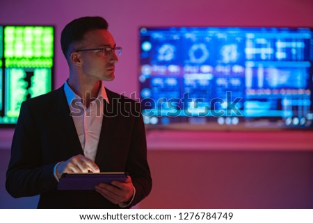 The man with a tablet standing on screens background