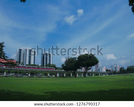 Cityscape under blue sky - grass field, train tracks and housing
