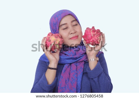 the woman smiled happily after getting two dragon fruit in her hand