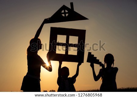 Happy children standing on the field at the sunset time. They build a house. Concept of friendly family.