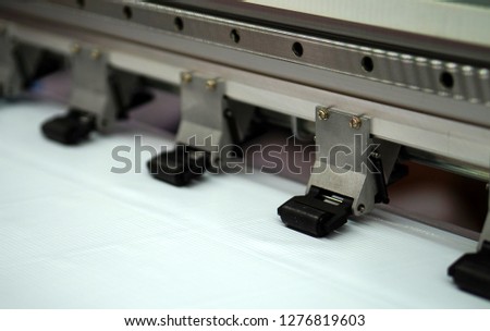 view of  Closeup of Large Inkjet printer in working with multicolor cmyk colors on vinyl banner                               