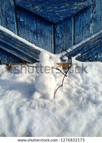 Winter landscape with a snowman at the vintage fence.