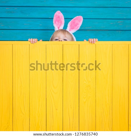 Funny kid wearing Easter bunny. Child holding wooden board banner. Spring holidays concept