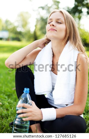 Young woman drinking water after training
