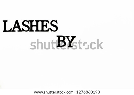 close-up of a black signboard on a white wall "Lashes by"