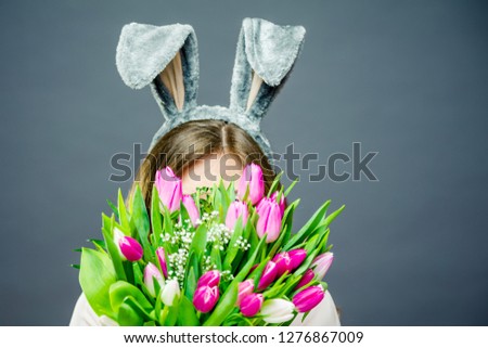 Young woman at home easter celbration concept in a bunny ears holding and buquet of tulips