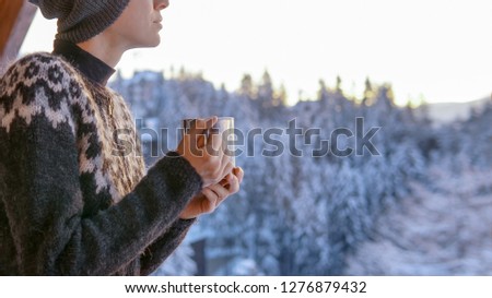 Young woman drinknig coffee with a view of the winter mountain landscape 
