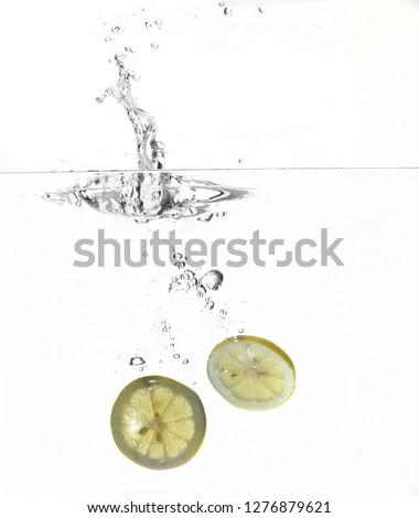 Fresh slices of lemon splash in water isolated on white background