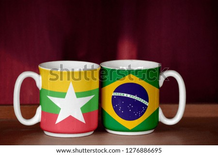 Brazil and Myanmar flag on two cups with blurry background