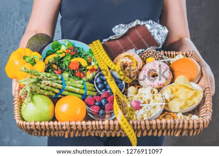 Healthy young woman looking at healthy and unhealthy plates of food, trying to make the right choice 