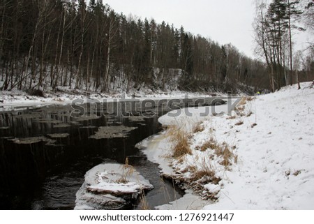 River Salaca with snow and floating ice. Cold winter time. tree reflections in dark water