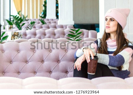Relaxed woman drinking coffee. Girl in casual style enjoy relaxing in modern cafe with pastel pink interior