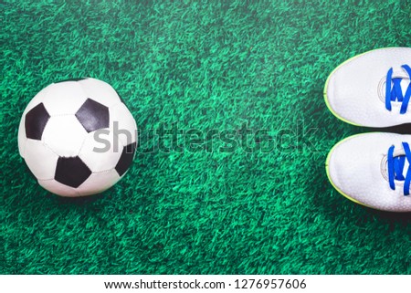 Soccer ball, white cleats against green artificial turf, top view with copy space, football concept