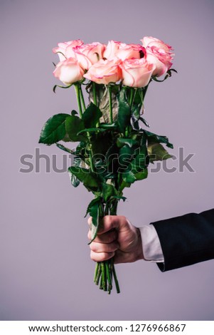 Close up photo of male hand holds the bouquet of roses. Celebration, holidays and gifts concepts. St Valentines dat. Lovers day
