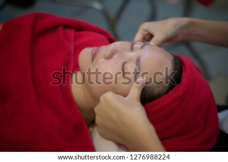 Beautiful young women getting a face treatment massage in massage salon.