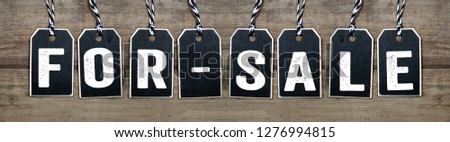 Wooden black hang tags on wooden background with for-sale
