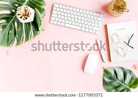 Flat lay home office desk. Female workspace with computer,  tropical palm leaves  Monstera, accessories on pink background. Top view feminine background. 