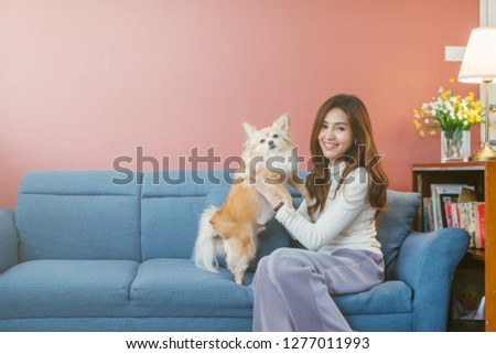 Portrait of young asian woman holding  her dog chihuahua on sofa at home.