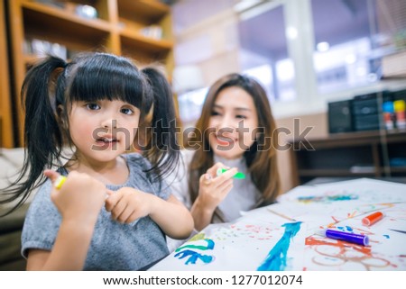 Cute little girl painting a picture with mother at home