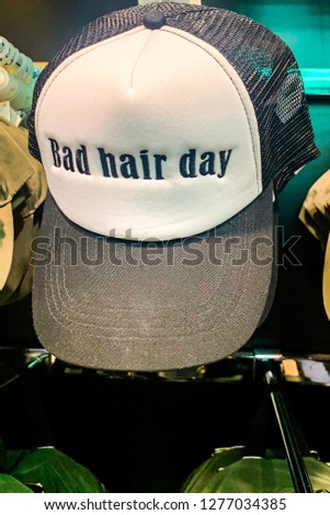 A baseball cap in a shop display with the words bad hair day written on it.