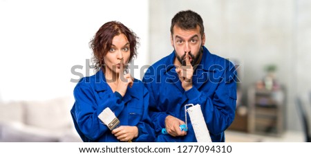 Painters showing a sign of silence gesture putting finger in mouth in house