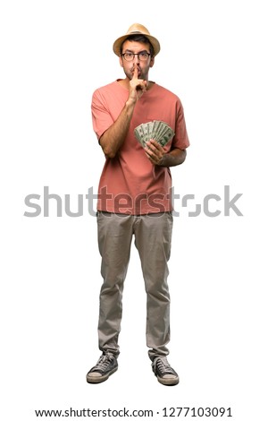 Man holding many bills showing a sign of silence gesture putting finger in mouth on isolated white background