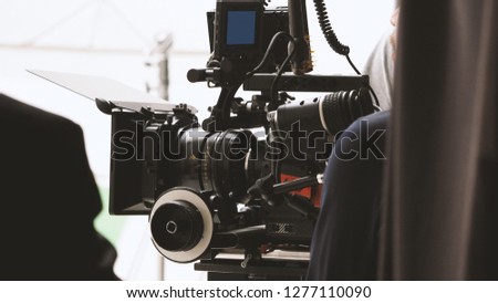 Behind the shooting or filming video movie and film production crew team setting up camera on tripod and professional equipment in studio for offline tv commercial or online web film recording.