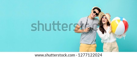 Playful Asian couple in summer casual clothes with beach accessories studio shot isolated on light blue banner background with copy space
