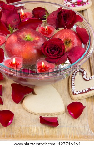 Valentine heart candles in bowl with rose petals and apple