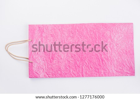 Light pink paper shopping bag. Luxury gift bag of pink color with rope handles on light background, horizontal image.