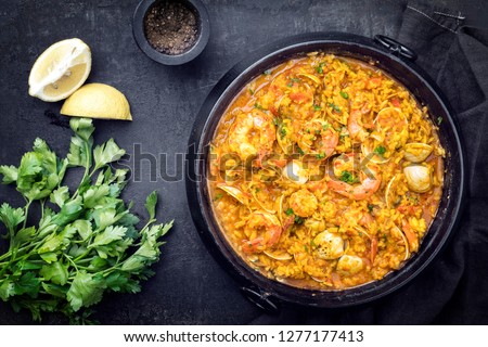 Traditional Portuguese arroz caldoso con almejas with shrimps and calm as top view in a cast-iron pot  Royalty-Free Stock Photo #1277177413