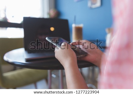 Closeup image of a woman holding , using and touching a smart phone while drinking coffee