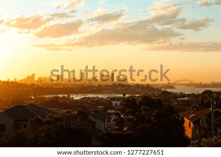 Magical glowing orange sunset over the skyline of Sydney with Harbour Bridge as seen on a summer evening from Dover Heights (Sydney, Australia)