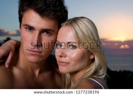 Portrait of loving young couple hugging by sea at dusk