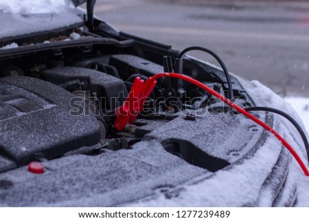 Quickly charge the car battery with jumper cables and another car. Open car hood with battery wires in snowy weather. Jump-Starting the Dead Battery. Royalty-Free Stock Photo #1277239489