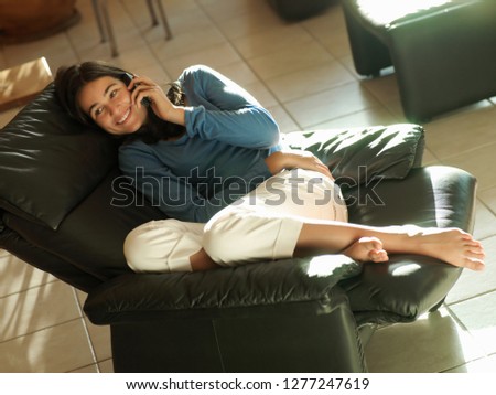 Teenage girl in reclining leather armchair at home using mobile phone Royalty-Free Stock Photo #1277247619
