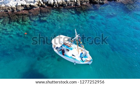 Aerial drone photo of traditional fishing boat docked in famous port of Mykonos island with emerald clear sea, Cyclades, Greece