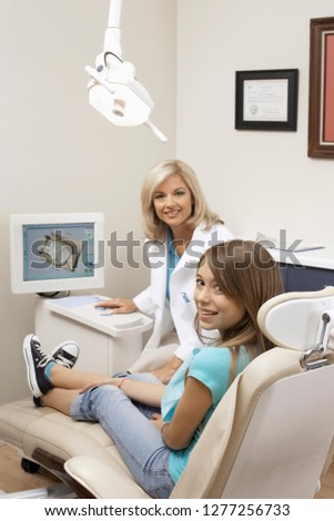 Female dentist in dental surgery talking to teenage patient in chair